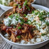 Fork-tender Pulled Pork Bowl topped with crunchy coleslaw and drizzled with smoky barbecue sauce, ready to eat.