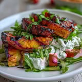 Grilled peach and burrata salad with arugula, cherry tomatoes, and balsamic glaze.