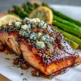 A golden salmon fillet rests on a bed of vibrant green asparagus spears, glistening with rich garlic butter sauce.  