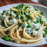 Lemon zest and sweet peas mingle in a light ricotta sauce, coating tender linguine for a refreshing vegetarian meal.  
