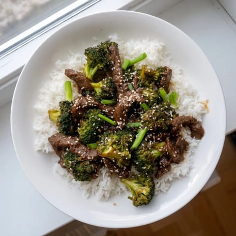 Close-up of homemade Beef and Broccoli featuring glistening sauce, colorful broccoli, and golden seared beef slices ready to serve.