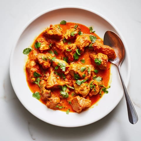 Close-up of Chicken Tikka Masala in a skillet, garnished with fresh cilantro and served with fluffy rice.