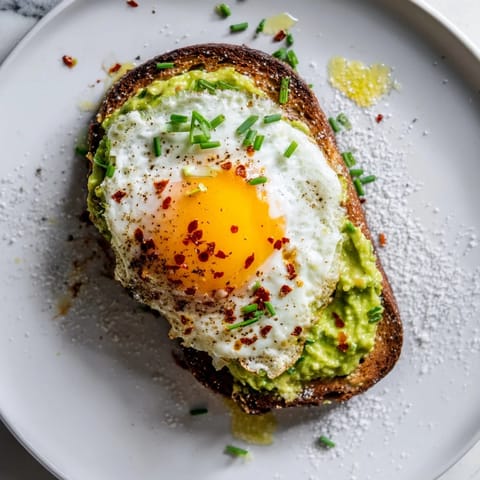Two slices of crispy avocado toast with poached eggs and chili flakes for breakfast.