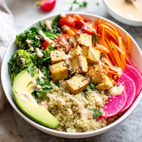 Steamed broccoli, fresh avocado slices, and shredded carrots create colorful sections over quinoa in a nourishing, restaurant-style Buddha Bowl.