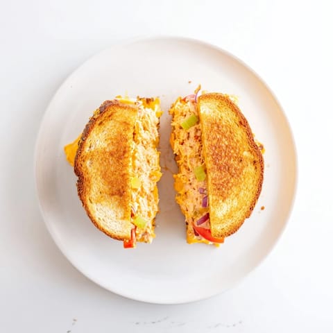 A close-up of a Spicy Tuna Melt sliced in half on a rustic plate.  