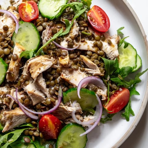 Fresh arugula, tender lentils, and juicy roasted chicken tossed with pickled onions in a zesty mustard dressing for a vibrant salad.  