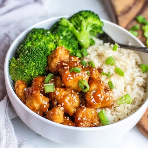 Steam rises from a serving of Sweet Chili Chicken Bowl featuring juicy chicken, crisp broccoli, and fluffy jasmine rice on a rustic table.