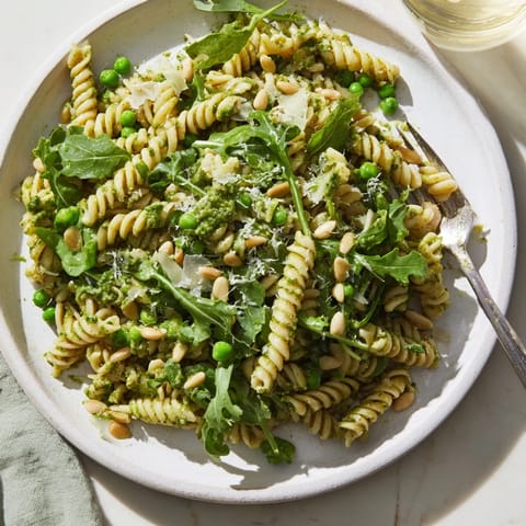 A bowl of chilled Spring Green Pesto Pasta Salad tossed with vibrant basil pesto and feta cheese, perfect for a picnic.