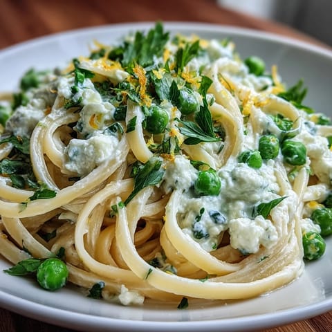 Lemon zest and sweet peas mingle in a light ricotta sauce, coating tender linguine for a refreshing vegetarian meal.  
