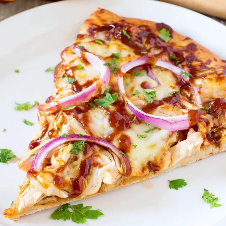 A close-up of delicious Chicken BBQ Pizza with red onions and cilantro, baked to perfection.