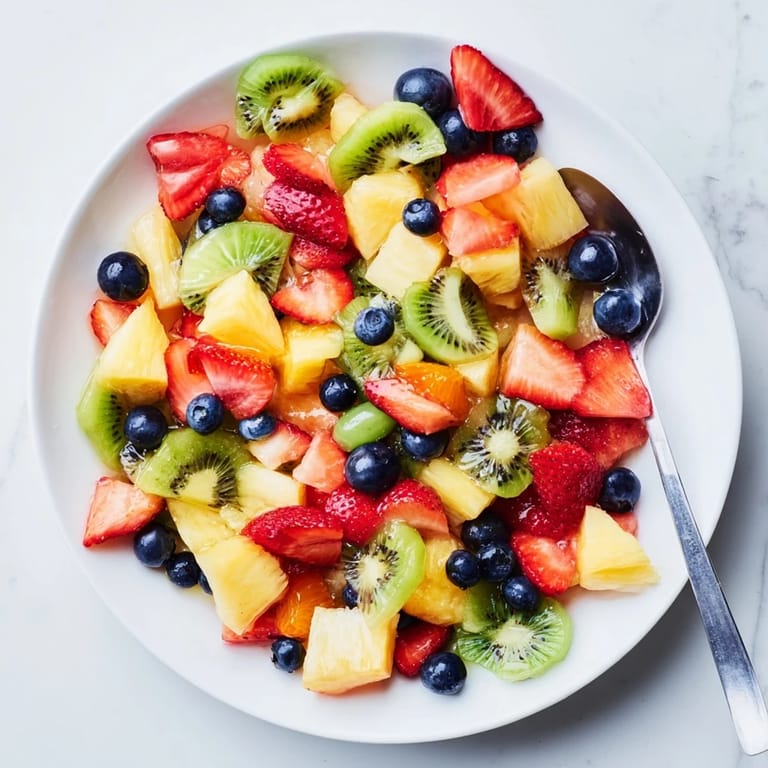 Colorful Fruit Salad featuring sliced kiwi and halved grapes, served as a refreshing summer dessert with a mint garnish.