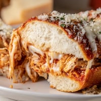 Golden-brown Chicken Parm Stuffed Garlic Bread boats, oozing with melted mozzarella and marinara sauce on a baking sheet.  