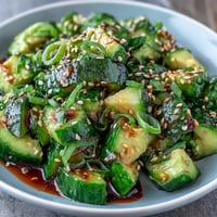 A vibrant smashed cucumber and avocado salad with sesame seeds, dressed in sesame oil and rice vinegar for a refreshing bite.